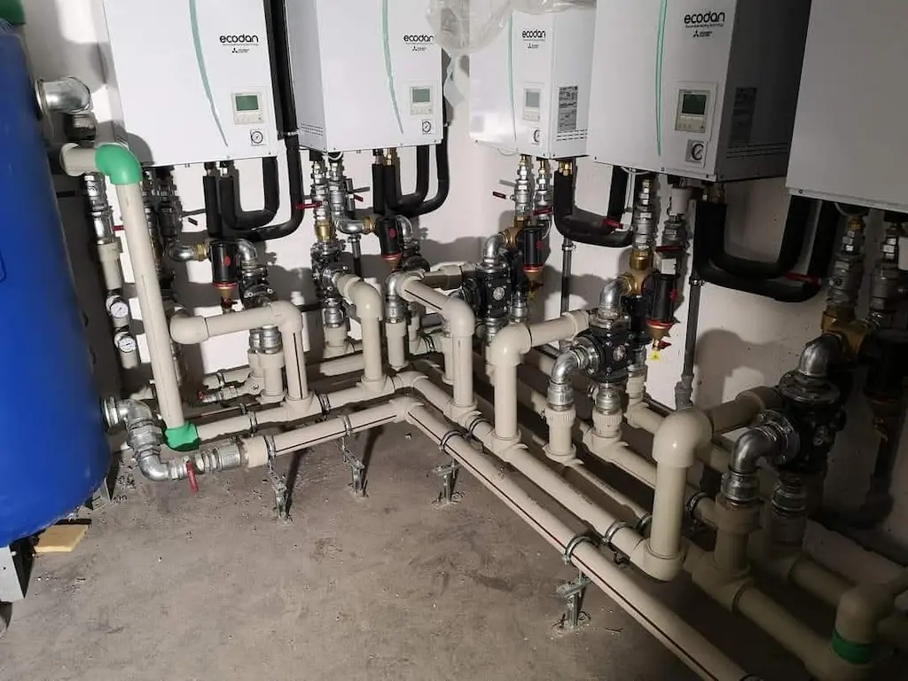 A Heat Builder Kft. által kivitelezett professzionális hőközpont, több Mitsubishi Ecodan hőszivattyú beltéri egység kaszkád kapcsolásával, precíz csővezeték-hálózattal és szigetelt szerelvényekkel.