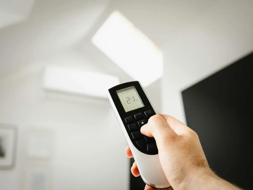 Légkondicionáló távirányítója használat közben, jelképezve a Heat Builder Kft. által kínált precíz és energiatakarékos hűtési megoldásokat.