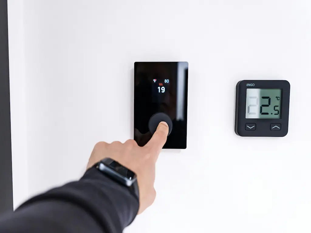 Modern, érintőképernyős okos termosztát és ENGO vezérlőegység a falon, amely a Heat Builder Kft. által telepített intelligens és energiatakarékos fűtési rendszer része.